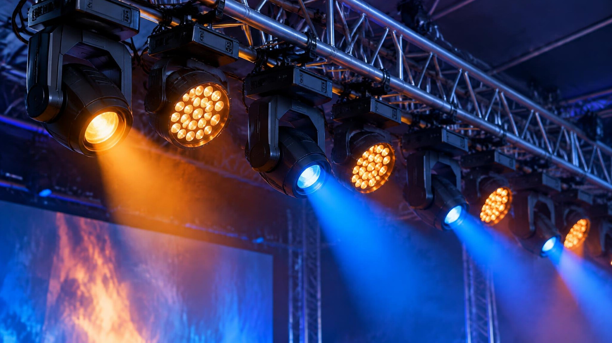Rows of stage lighting fixtures glowing warm orange and blue