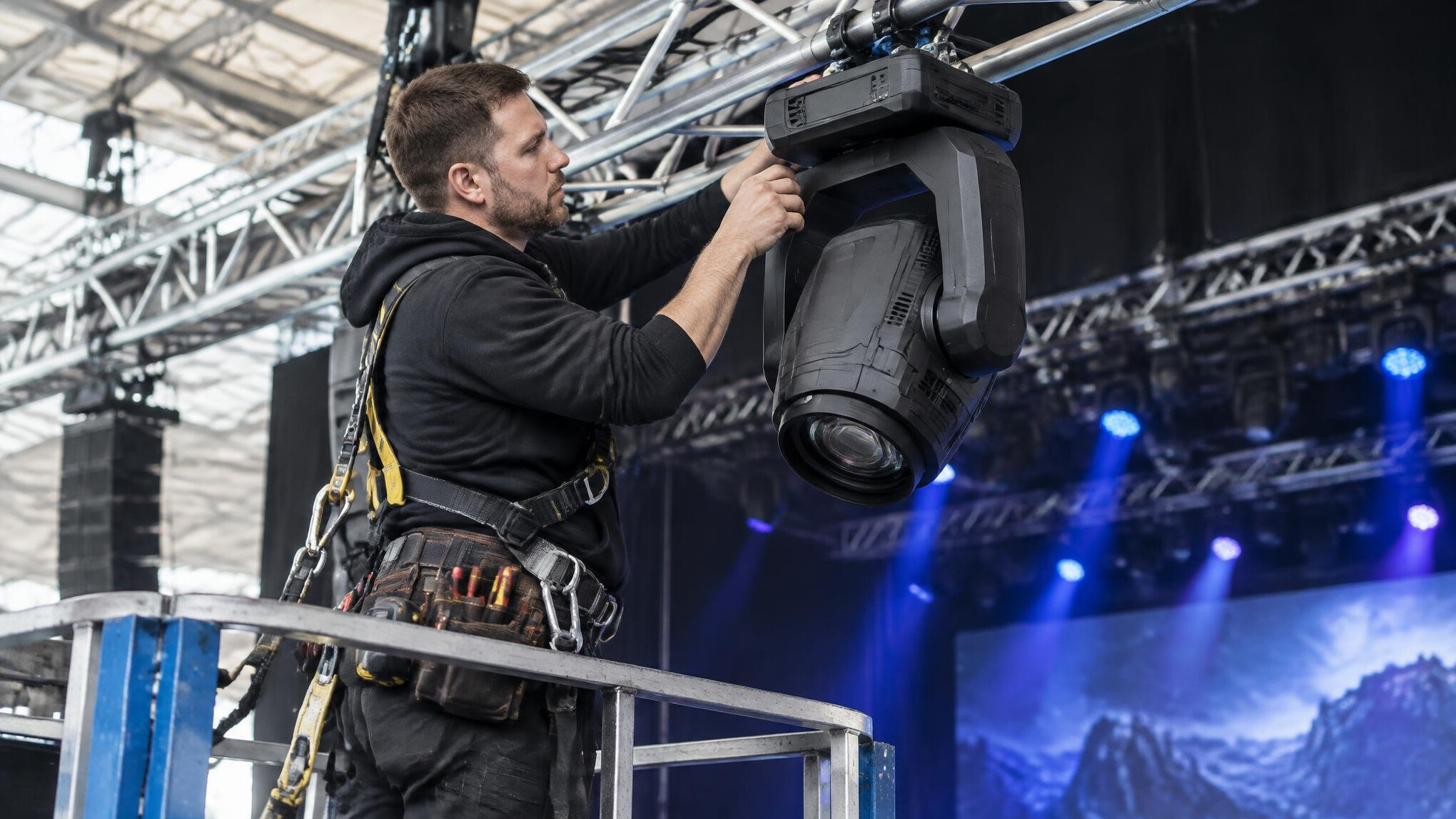 Technician adjusting stage lighting fixtures on a truss
